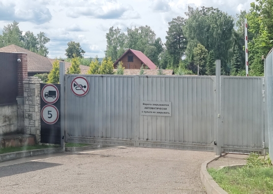 За газоном и деревьями, ухаживает садовник.